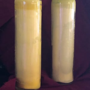 Könnte beinhalten: Zwei gelbe Glas-Votivkerzen in einem durchsichtigen Glasbehälter. Die Kerzen sind teilweise heruntergebrannt.