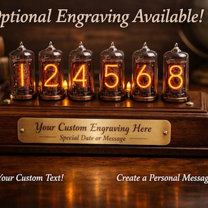 May include: A wooden digital clock with six glowing tubes displaying the numbers 1, 2, 4, 5, 6, and 8. The clock has a brass plate that reads "Your Custom Engraving Here". The text "Optional Engraving Available!" is at the top, with "Add Your Custom Text!" and "Create a Personal Message!" at the bottom.