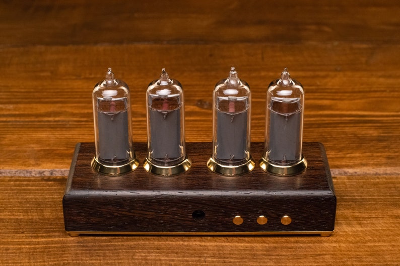 May include: Four clear glass Nixie tubes with black numerals on a dark wood base with gold accents. The tubes are lit and display the numbers 1, 2, 3, and 4.