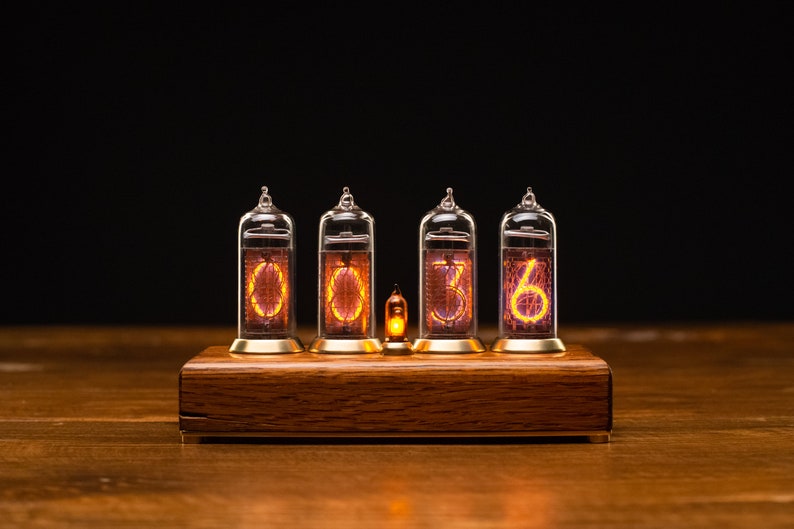 Puede incluir: Un reloj de madera con cuatro tubos Nixie que muestran la hora 00:36. Los tubos est&aacute;n iluminados con un c&aacute;lido brillo naranja.
