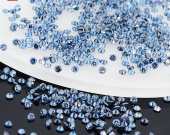 May include: A close-up view of a large quantity of loose blue diamonds. The diamonds are scattered on a white surface and a black surface.