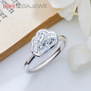 May include: A silver ring with a large, clear, cloud-shaped diamond. The ring is set on a white background.