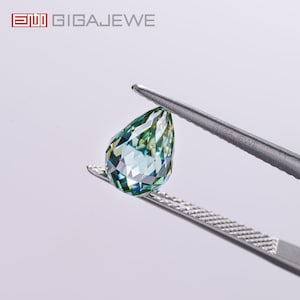 May include: A pear-shaped, faceted gemstone with a light blue and green color held by tweezers. The gemstone has multiple facets that reflect light. The logo "GIGAJEWE" is in the top left corner.