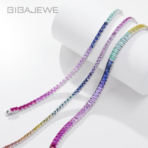 Peut inclure: Quatre bracelets de tennis ornés de pierres précieuses colorées. Chaque bracelet présente un dégradé de pierres, allant du rose au jaune, bleu et vert. Les bracelets sont posés sur un fond blanc. Le nom de la marque "GIGAEWE" est visible en haut à gauche.