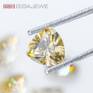 May include: A yellow triangular gemstone held by tweezers. The gemstone has many facets and is sparkling.