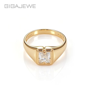 Puede incluir: Un anillo de oro con una piedra preciosa transparente de corte rectangular en un engaste de bisel. El interior de la banda está grabado con el texto Au585 y M1.00ct. El nombre de la marca GIGAJEWE aparece en la esquina superior izquierda.
