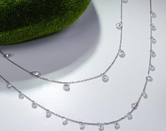 May include: A silver chain necklace with two strands and small, clear, round stones hanging from each strand.