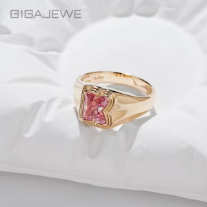 Op de afbeelding: Een gouden zegelring met een opvallende letter K gevormd uit roze edelstenen. De ring is van gepolijst goud met het keurmerk Au585 aan de binnenzijde gegraveerd. De merknaam GIGAJEWE is zichtbaar in de linkerbovenhoek van de afbeelding.