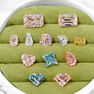 Peut inclure: Une collection de douze pierres précieuses en vrac de différentes tailles et couleurs, incluant des teintes roses, bleues et jaunes, disposées sur un plateau de présentation en velours vert. Les pierres présentent des facettes variées.