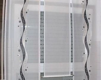 Può includere: Tende bianche e trasparenti con un design ondulato nero e argento. Le tende sono appese a una finestra con una cornice bianca.