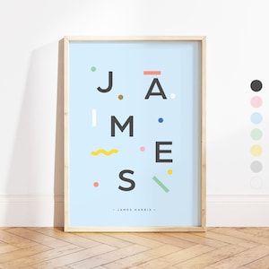 May include: A light blue framed print with the name "JAMES" spelled out in black letters with colourful geometric shapes around the letters. The text "JAMES HARRIS" is printed in black at the bottom of the print.
