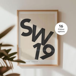 May include: A framed print featuring the text "SW19" in black against a light beige background. The text is in a bold, sans-serif font. The frame is a light wood colour. The print is available in 16 colour options.