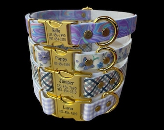 May include: A stack of four pet collars with gold-tone metal buckles. Each buckle is engraved with a name and phone numbers: Bella, Poppy, Juniper, and Luna. The collars feature various patterns including purple marble, blue flowers, plaid, and gingham.