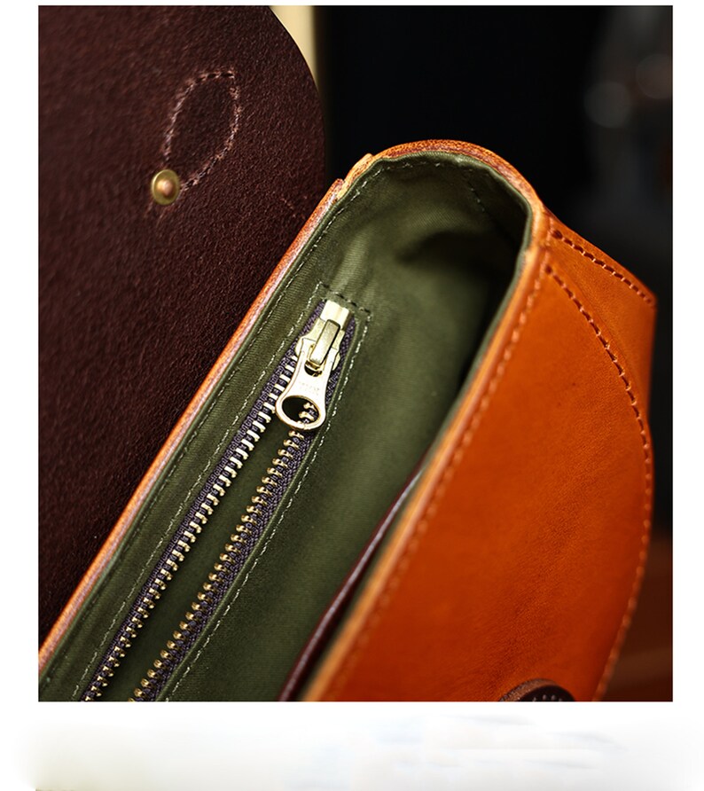 May include: Close-up of the inside of a brown leather bag with a gold zipper. The bag has a green lining.