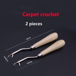 May include: Two carpet crochet tools with light-colored wooden handles and silver metal hooks. The text "Carpet crochet" and "2 pieces" is visible. One tool measures 15 cm in length, while the hook widths are labeled as 5.5 mm and 6.5 cm.