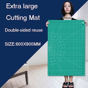 May include: A large green self-healing cutting mat with a grid pattern and a circular design in the center. The mat is 600x900mm and is double-sided for reuse.