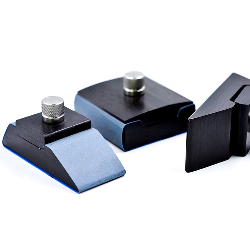 May include: Three black woodworking tools with blue rubber pads and silver knobs. The tools are designed for clamping and holding wood.