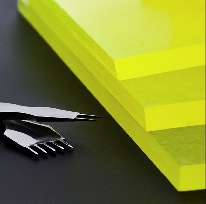 May include: Three sheets of bright yellow translucent acrylic plastic stacked on top of each other. The acrylic sheets are smooth and glossy.