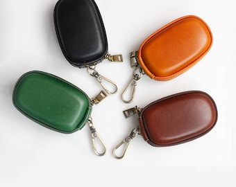 May include: Four leather keychains with zippered pouches in black, green, brown, and orange. Each keychain has a metal ring and a hook.