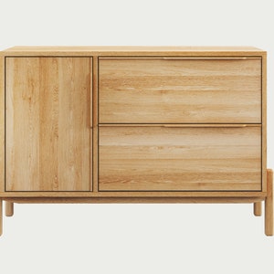 May include: A light wood cabinet with two drawers and a door. The cabinet has a simple design with a light wood finish and brass hardware.