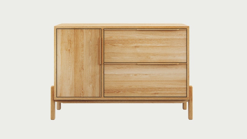 May include: A light wood cabinet with two drawers and a door. The cabinet has a simple design with a light wood finish and brass hardware.