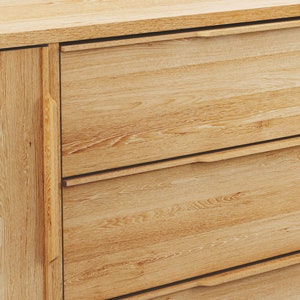 May include: A wooden cabinet with three drawers and a single door. The cabinet is made of light wood with a natural finish. The drawers have simple, recessed handles.
