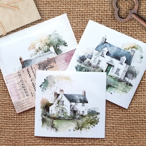 Könnte beinhalten: Drei Aquarelle von weißen Häusern mit grünem Zierleisten und grünem Laub. Die Häuser sind auf weißen Karton gemalt.