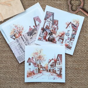 Könnte beinhalten: Drei Aquarell-Illustrationen von malerischen europäischen Gebäuden mit roten Ziegeldächern und weißen Wänden. Die Illustrationen sind auf weißem Karton gedruckt und eignen sich perfekt zum Scrapbooking, Kartenbasteln oder anderen Bastelprojekten.