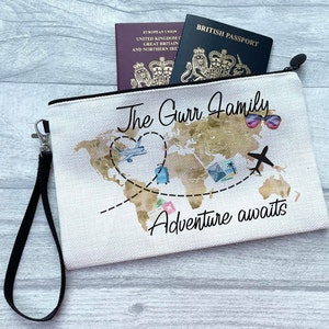 May include: White canvas travel makeup bag with a black zipper and a black strap. The bag features a gold world map with a heart shape around it, two airplanes, and the text "The Gurr Family Adventure awaits".