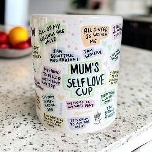 May include: White ceramic mug with a colorful design featuring positive affirmations and the text "Mum's Self Love Cup".
