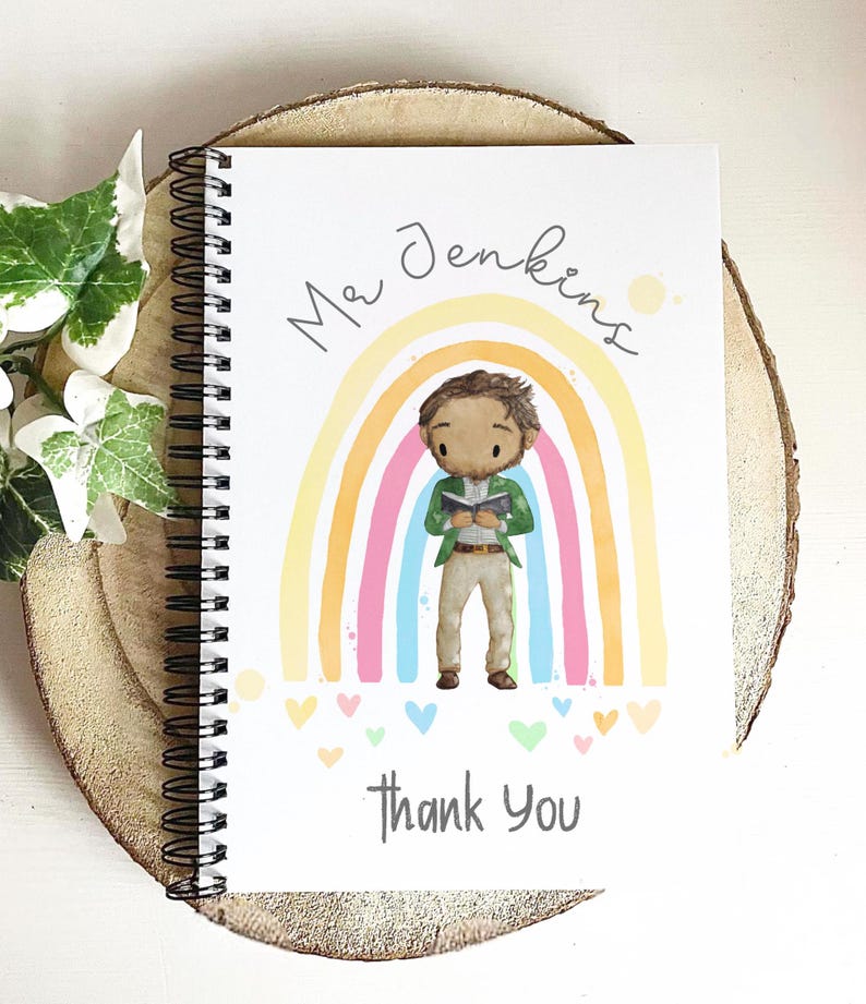 May include: White spiral-bound notebook with a colorful rainbow design and the words "Mr. Jenkins" and "Thank You." The illustration features a cartoon figure of a person standing in front of the rainbow. Small hearts are scattered at the bottom.