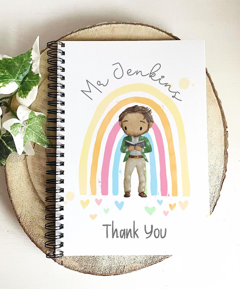 May include: Spiral-bound notebook with a colorful illustration. The cover features a cartoon teacher figure in front of a rainbow, with the name "Mr Jenkins" and the words "Thank You". The design includes hearts and a light wood background.