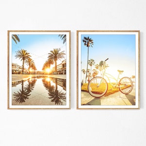 May include: Two framed prints, one showing a street lined with palm trees and a reflecting pool, the other showing a bicycle parked on a sidewalk with palm trees in the background.
