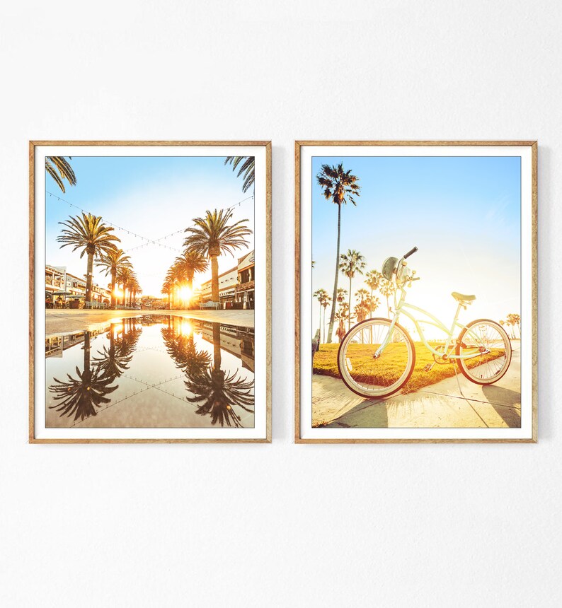 May include: Two framed prints, one showing a street lined with palm trees and a reflecting pool, the other showing a bicycle parked on a sidewalk with palm trees in the background.