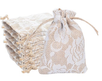 Könnte beinhalten: Ein Stapel kleiner, weißer und beigefarbener Jutesäckchen mit einem floralen Spitzenmuster. Die Säckchen eignen sich perfekt zum Verpacken von kleinen Geschenken oder Gastgeschenken.
