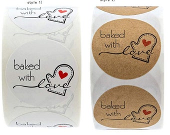May include: Two rolls of round stickers with the text "baked with love" and a red heart in a black oven mitt. The stickers on the left roll are white and the stickers on the right roll are brown.