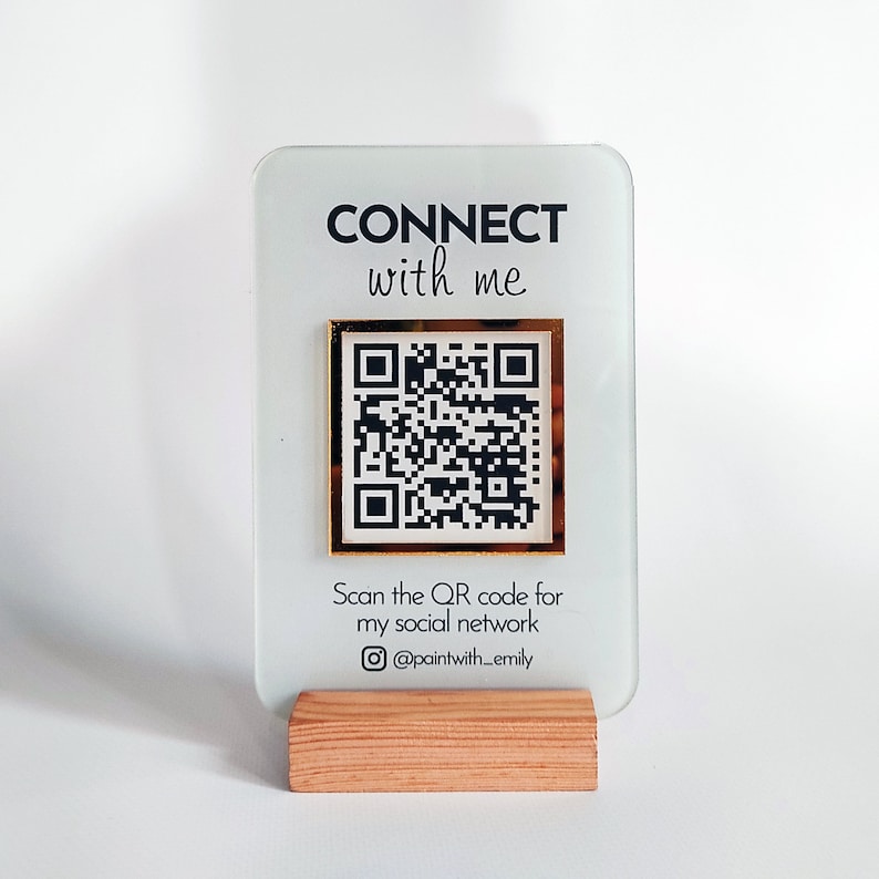 May include: A white acrylic sign with gold trim and a black QR code. The sign reads "CONNECT with me" and "Scan the QR code for my social network @paintwith_emily".