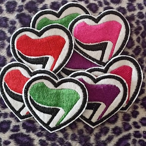 Può includere: Sei toppe ricamate a forma di cuore con un design stilizzato di una scarpa con tacco alto. Le toppe sono in rosso, rosa, verde, viola e due tonalità di verde.