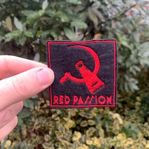 Può includere: Toppa ricamata rossa con un design a martello e falce rosso e il testo "RED PASSION" su sfondo nero.