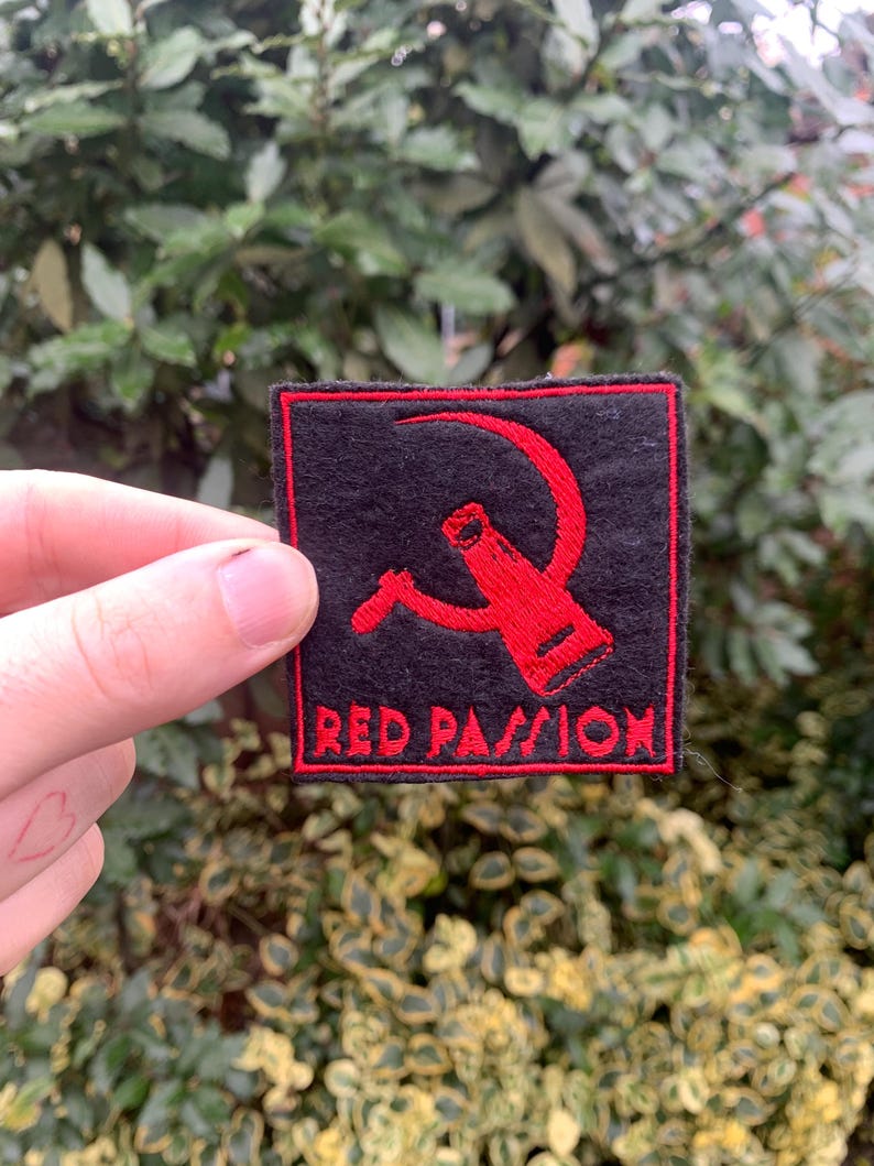 K&ouml;nnte beinhalten: Roter gestickter Aufn&auml;her mit einem roten Hammer-und-Sichel-Motiv und dem Text "RED PASSION" auf schwarzem Hintergrund.