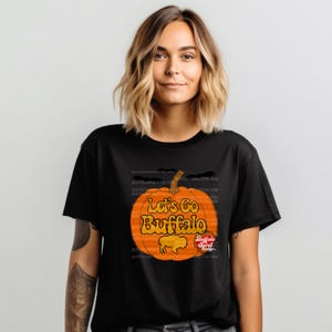 May include: Black t-shirt with a graphic of an orange pumpkin with the text "Let's Go Buffalo" and a buffalo silhouette. The text "Buffalo Spirit Designs" is also included.