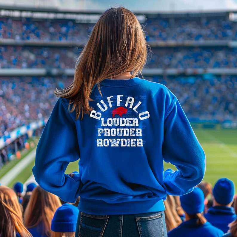 Puede incluir: Una sudadera azul con un gr&aacute;fico blanco en la espalda que dice "Buffalo Louder Prouder Rowdier" con una silueta de b&uacute;falo roja dentro de la palabra "Buffalo".