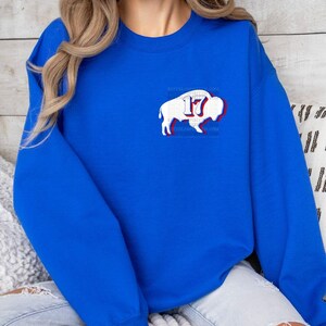 May include: Royal blue sweatshirt with a white buffalo silhouette and the number 17 in red and white. The buffalo is outlined in red and has a white outline around the number 17.