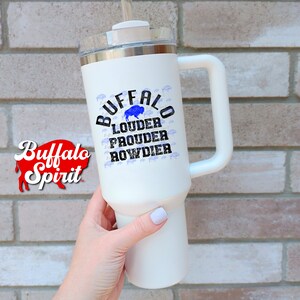 Puede incluir: Taza de viaje de acero inoxidable blanca con un gr&aacute;fico de silueta de b&uacute;falo negro y azul y el texto "Buffalo Louder Prouder Rowdier".