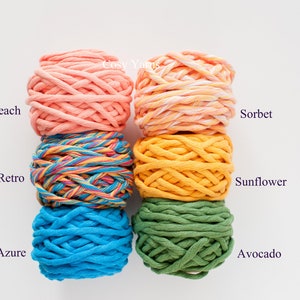 May include: Six balls of chunky cotton yarn in various colours, including peach, yellow, green, blue, and a multi-coloured yarn. The yarn is labelled with the names "Peach", "Sorbet", "Sunflower", "Avocado", "Azure", and "Retro".