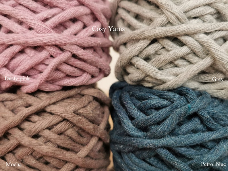 May include: Four balls of yarn in different colors: dusty pink, mocha, grey, and petrol blue. The yarn is labeled "Cosy Yarns".