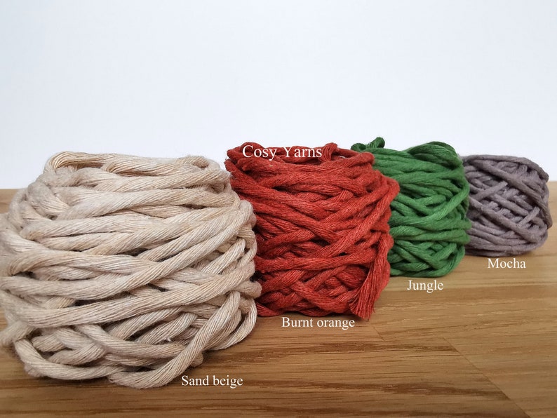 May include: Five spools of yarn in different colors: sand beige, burnt orange, jungle green, mocha, and a white label that says "Cosy Yarns".
