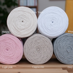 May include: Six spools of cotton yarn in different colours: natural, white, light pink, cappuccino, and grey. The yarn is labelled "Cosy Yarns".