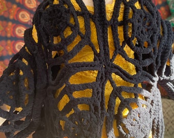May include: Black crochet cardigan with a large openwork design. The cardigan is made with thick yarn and has a loose fit.