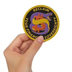 May include: A yellow and black embroidered patch with a purple snake wrapped around a dollar sign. The text on the patch reads "Reclaim Your Financial Sovereignty".